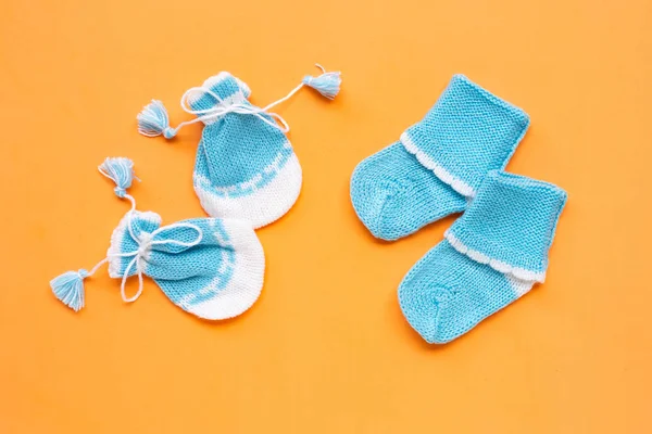 Guantes y calcetines de bebé sobre fondo naranja . — Foto de Stock