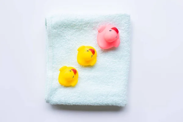 Juguetes de pato rosa y amarillo sobre una toalla verde suave, fondo blanco — Foto de Stock