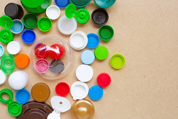 Colorful plastic bottle caps and plastic glass lid on plywood