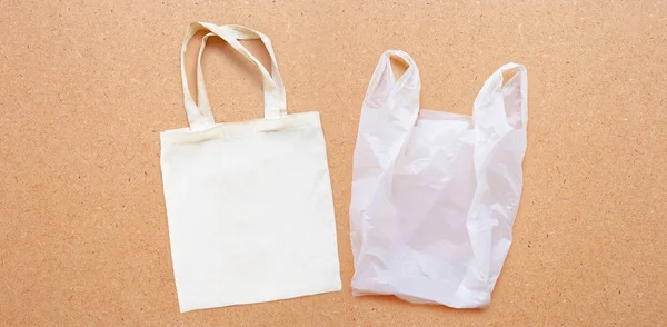 Saco de tecido branco com saco de plástico branco no fundo de madeira compensada . — Fotografia de Stock