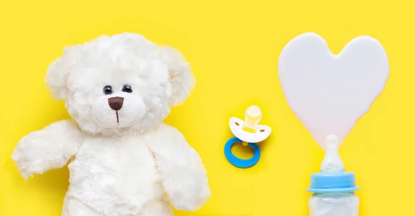 옐로에 장난감 곰을 가진 아기와 아기 젖꼭지를 위한 우유의 병 — 스톡 사진