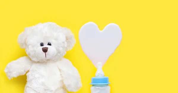 Garrafa de leite para bebê com urso branco de brinquedo no fundo azul . — Fotografia de Stock