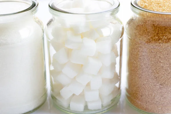 Различные виды сахара в стеклянной банке на белом — стоковое фото