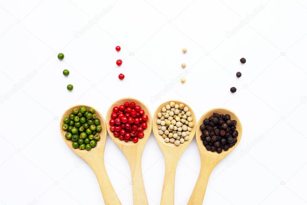 Green, red white and black peppercorns with wooden spoon on whit