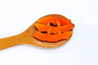 Beyaz arka planda ahşap kaşıkla zerdeçal köklerinin kesilmesi.