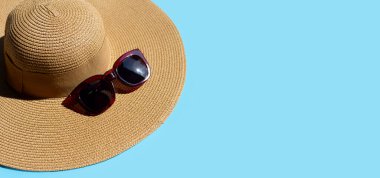 Mavi arka planda güneş gözlüklü yaz şapkası. Tatilin tadını çıkar. Boşluğu kopyala