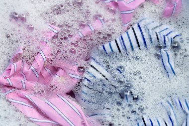 Renkli kıyafetlerin üst görüntüsü toz deterjanıyla sulandırılmış. Çamaşır konsepti