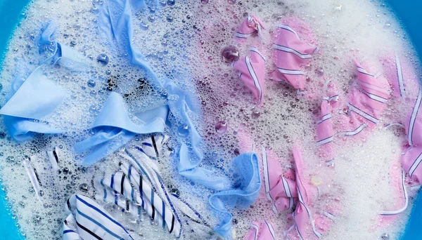 色の服のトップビューは 粉末洗剤水の溶解に浸かります ランドリーコンセプト — ストック写真