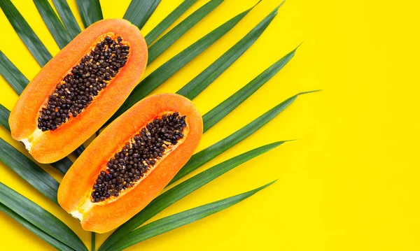 Tropikal palmiye yaprakları üzerinde tatlı olgun papaya. Kopyalama alanı olan üst görünüm