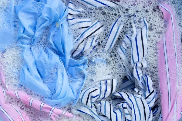 色の服のトップビューは 粉末洗剤水の溶解に浸かります ランドリーコンセプト — ストック写真