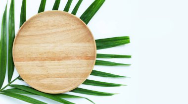 Beyaz zemin üzerinde tropikal palmiye yaprakları üzerinde boş ahşap tabak.
