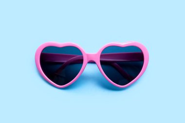 Mavi arka planda pembe kalp şeklinde güneş gözlüğü. Üst görünüm