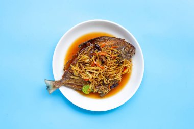 Kızarmış balık, zencefilli ve soya soslu beyaz tabak ve mavi arka plan. Üst görünüm