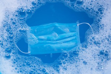 Koruyucu tıbbi maske yıkanmadan önce toz deterjanıyla yıkanır. Hijyen koronavirüsü (Covid-19) koruma konsepti. Üst görünüm