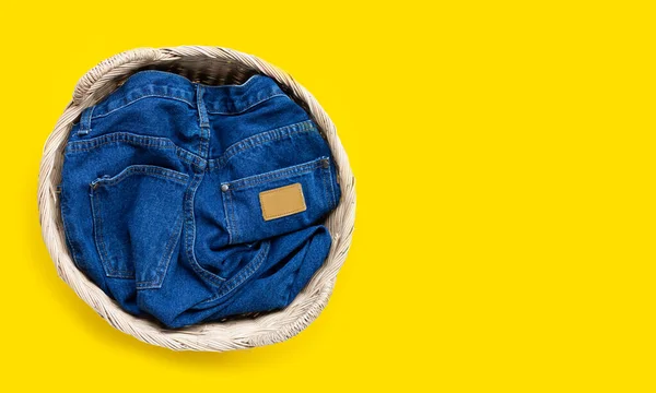 黄色の背景に洗濯バスケットのジーンズ トップ表示 — ストック写真