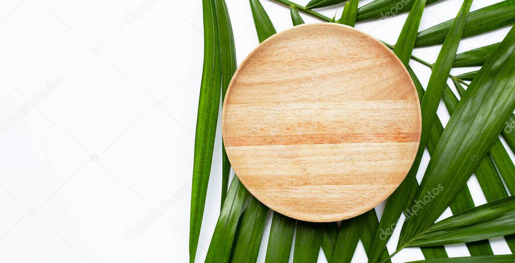 Empty wooden plate on tropical palm leaves on white background. Top view
