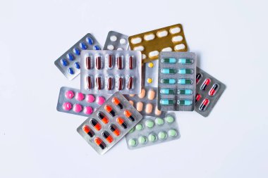 Beyaz arka planda çeşitli kapsül ilaçları, haplar ve tabletler..