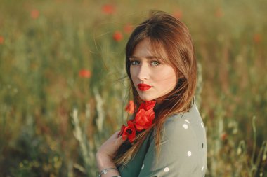 Gelincik tarlasında gitarı olan yeşil elbiseli bir kız.