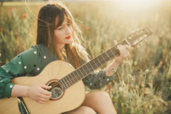 穿着绿色衣服 在罂粟地里拿着吉他的女孩 — 图库照片