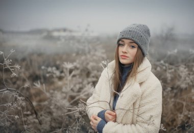 Buzlu tarlada beyaz kürklü bir kız.