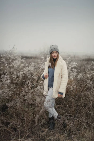在冰冷的田野上穿着白色皮毛外套的女孩 — 图库照片