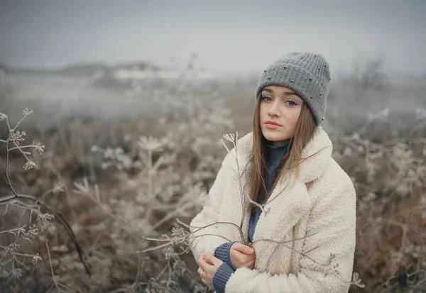 在冰冷的田野上穿着白色皮毛外套的女孩 — 图库照片