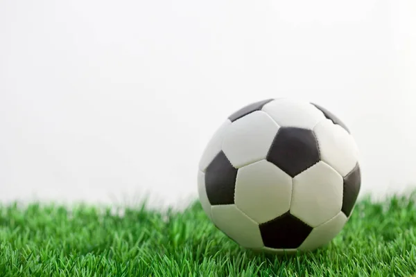 Beyaz arka planda yeşil çimlerde futbol topu