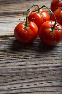 Eski ahşap bir masanın sağ üst köşesinde taze organik olgun domatesler. Metin ve / veya logo için kullanışlı kopyalama alanı