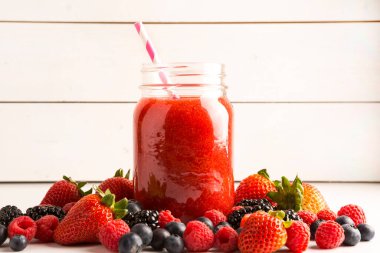 Güzel kırmızı ahududu, böğürtlen, çilek ve böğürtlen suyu cam kavanozda taze böğürtlen ve kağıt kamışla kaplanmış.