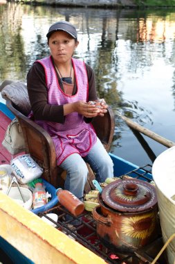 Xochimilco, Mexico City, Mexico - 2019: A woman in atrajinera (a local type of boat) sells local food to people in other trajineras on city canal