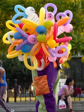 Cordoba, Arjantin - 2016: Palyaço kostümlü kadın Katedralin önünde, San Martin meydanında hayvan şeklinde renkli balonlar satıyor.