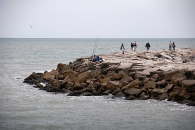 Mar del Plata, Buenos Aires, Arjantin - 2018: Şehir sahilinde iki erkek balık tutuyor. Mar del Plata ülkenin başlıca turistik yerlerinden biridir.