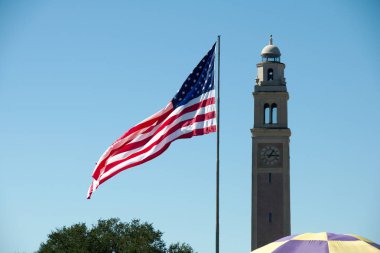 Arka planda Savaş Anıtı Kulesi ile Louisiana State Üniversitesi'nde Parade Ground'da Amerika Birleşik Devletleri Bayrağı, Baton Rouge, Louisiana, ABD.