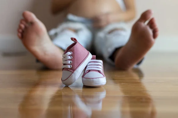 Future mom feet with little baby shoes