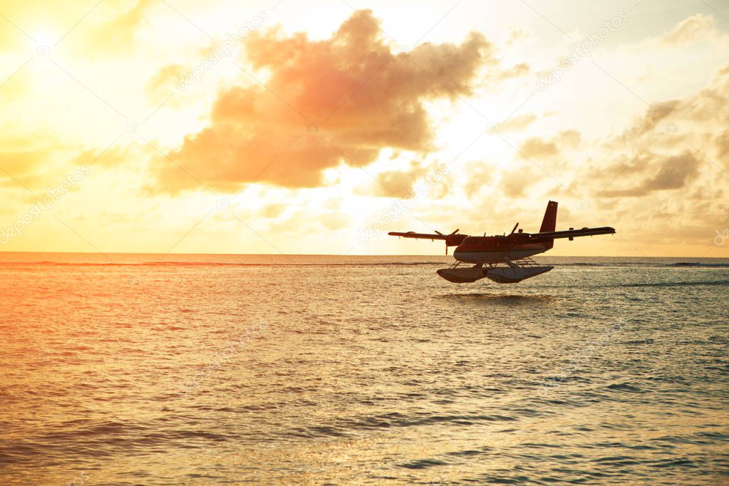 Summer sunrise with seaplane. Landing seaplane on the seashore. Calm scenery on morning sea.