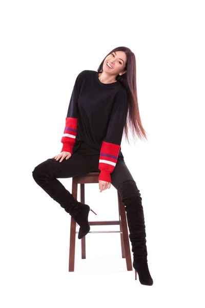 Pretty woman in black suit isolated on white background. Cute brunette sits on the chair at white studio. Close up portrait of sporty and beautiful woman. — Stock Photo, Image