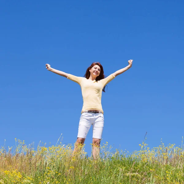 La libertà delle persone concetto di successo. Donna felice sogna di volare sui venti. Paesaggio di erba e fiore campo estivo nella giornata di sole. Natura bellezza sfondo, cielo blu e prato verde. Stile di vita all'aperto . — Foto Stock