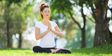 Yoga dışarıda. Yoga egzersizleri yapan, parkta meditasyon yapan mutlu bir kadın. Yoga meditasyonu. Sağlıklı yaşam tarzı ve rahatlama kavramı. Çimenlerde yoga yapan güzel bir kadın.