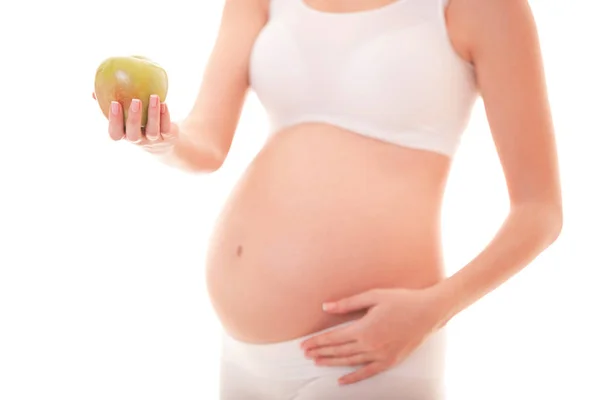 孕妇触摸她的大肚子,手里拿着苹果在白色背景上孤立的图像。特写美丽的孕妇身体。母性,怀孕。妇女期待婴儿 — 图库照片