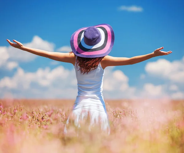 Donna felice godendo la vita nel campo con i fiori. Bellezza della natura, cielo nuvoloso blu e campo colorato con fiori. Stile di vita all'aperto. Il concetto di libertà. Donna nel campo estivo — Foto Stock