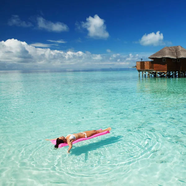 Vrouw zwemmen en ontspannen op opblaasbare matras in de zee. Gelukkig eiland levensstijl. Wit zand, kristalheldere zee van tropisch strand. Vakantie in Paradise. Ocean beach ontspannen, reizen naar de Malediven eilanden — Stockfoto