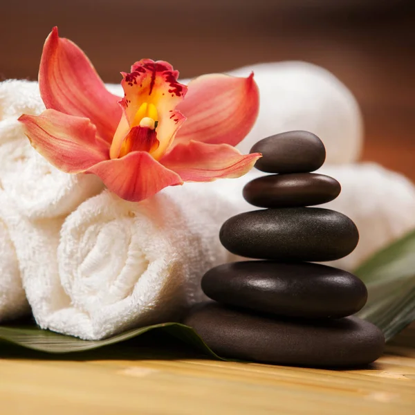 Uzdrowisko. Białe ręczniki na egzotycznych roślin, piękne kwiaty orchidei i równoważące kamienie do relaksu masażu spa i leczenia ciała. Azjatycka medycyna z aromatem i kamienną terapią dla piękna zdrowego ciała — Zdjęcie stockowe