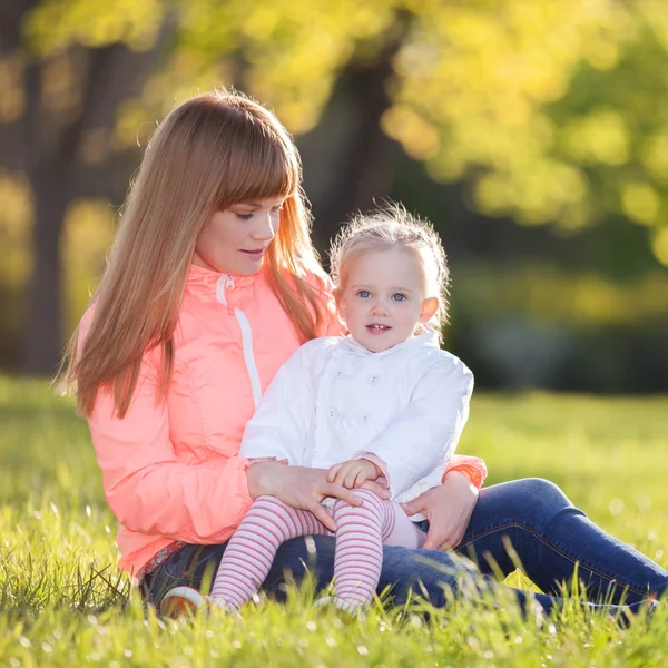 Madre e figlia passeggiano nel parco autunnale. Scena naturalistica di bellezza con sfondo colorato, alberi gialli e foglie nella stagione autunnale. Stile di vita all'aperto autunno. Felice relax in famiglia su erba verde — Foto Stock