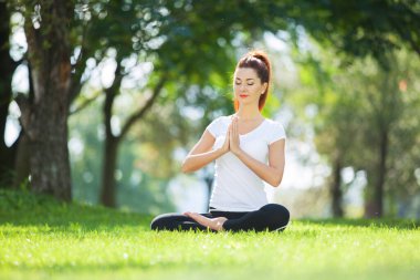 Yoga dışarıda. Yoga egzersizleri yapan, parkta meditasyon yapan mutlu bir kadın. Yoga meditasyonu. Sağlıklı yaşam tarzı ve rahatlama kavramı. Çimenlerde yoga yapan güzel bir kadın.