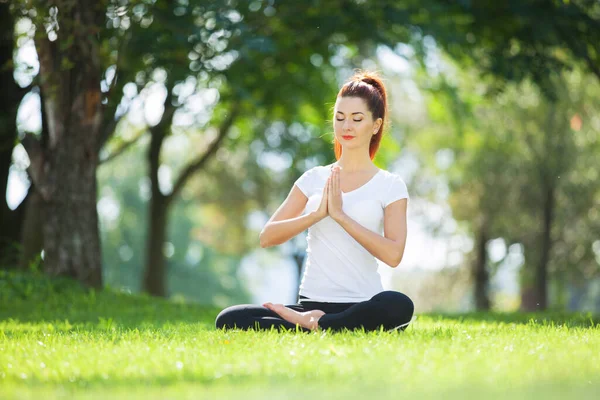 ヨガ屋外 幸せな女性は 公園で瞑想ヨガの演習を行う 自然の中でヨガの瞑想 健康的なライフスタイルとリラクゼーションの概念 可愛い女が草の上でヨガを練習 — ストック写真
