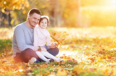 Sonbahar parkında mutlu bir baba ve kız. Aile hayatı olan güzel doğa manzarası. Mutlu aile yeşil çimlerin üzerinde birlikte dinleniyor, dışarıda eğleniyor. Aile hayatında mutluluk ve uyum.