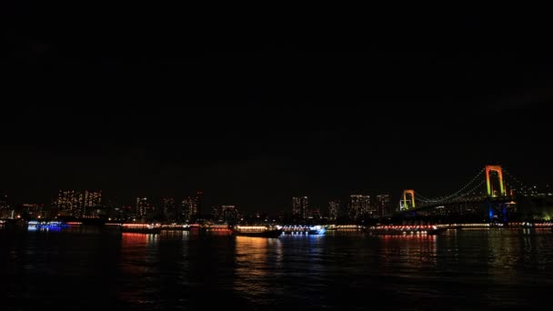 Barcos flotantes iluminados cerca del colorido puente en Odaiba Tokio — Vídeos de Stock