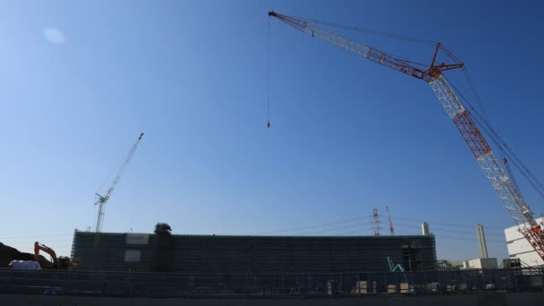 Grues mobiles derrière le ciel bleu à la construction large plan en cours — Video