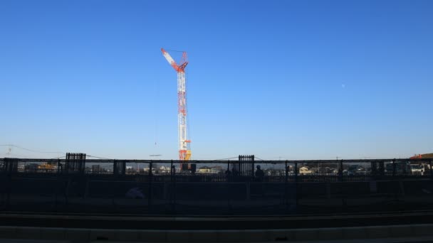 Grúas en movimiento detrás del cielo azul en el plano ancho en construcción — Vídeos de Stock