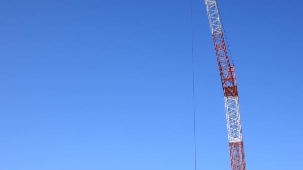 Bewegende kranen achter de blauwe lucht bij de aanbouw — Stockvideo